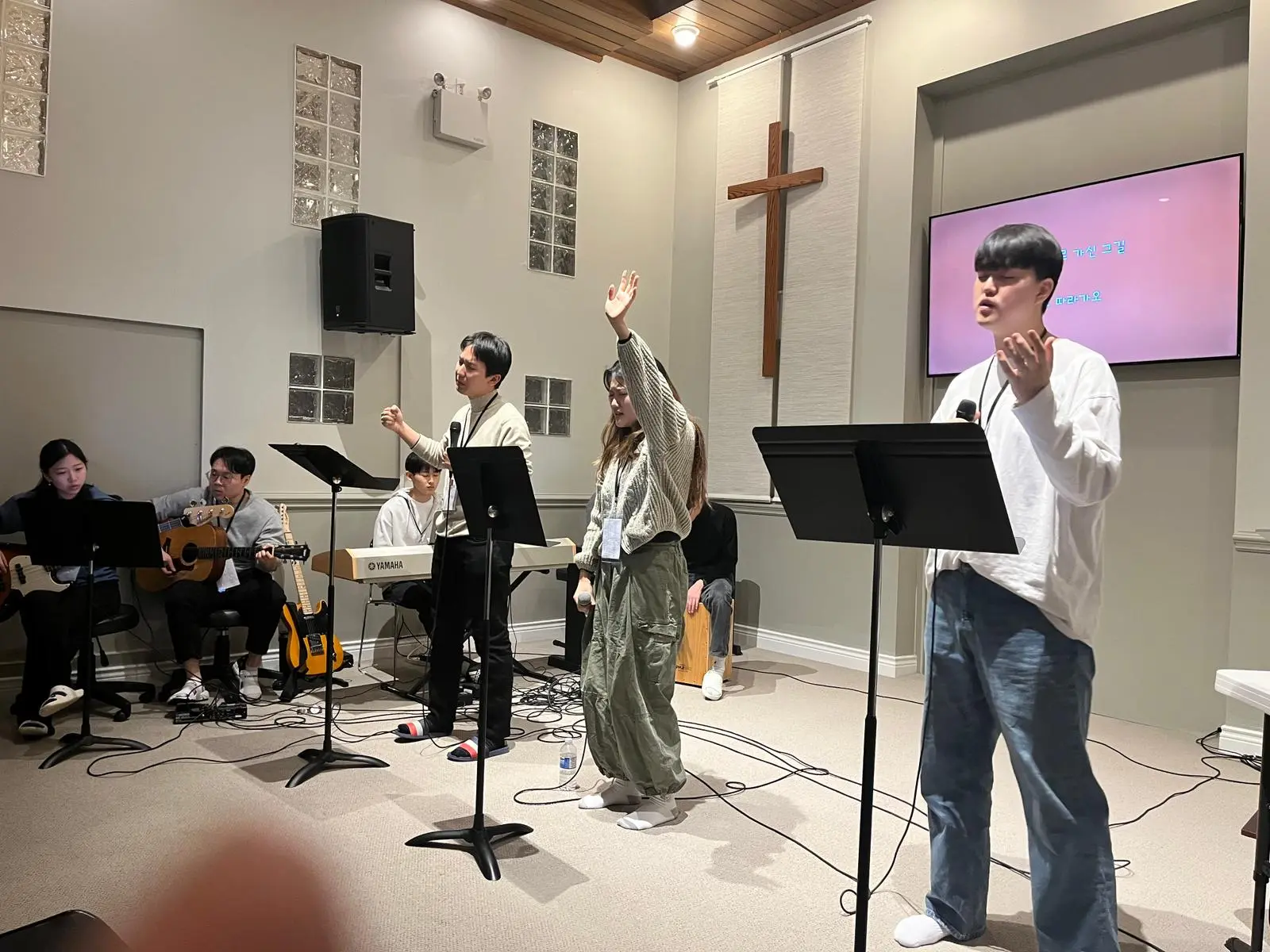 Young adults leading worship with microphones and musical instruments